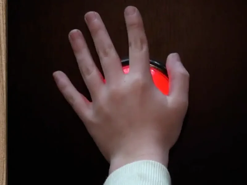 Une main appuie sur un gros bouton rouge lumineux, sur un défi d'adresse de Défis Pirate Perpignan