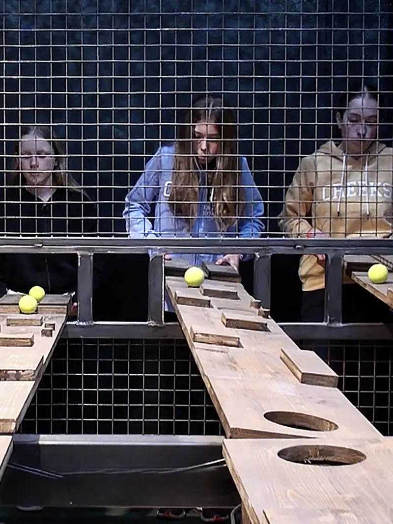Trois joueuses concentrées sur un défi d'adresse, des balles posées sur des planches de bois