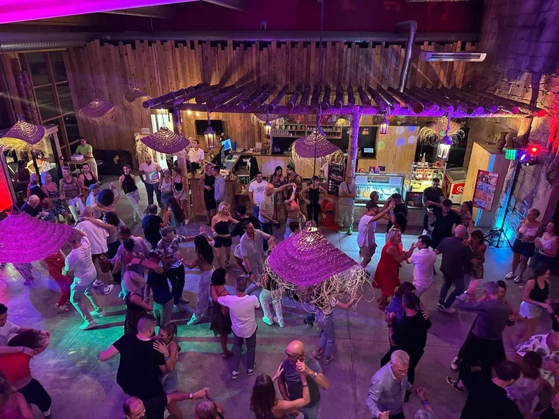 Vue de la mezzanine : les danseurs devant le bar, sous les lampes en paille