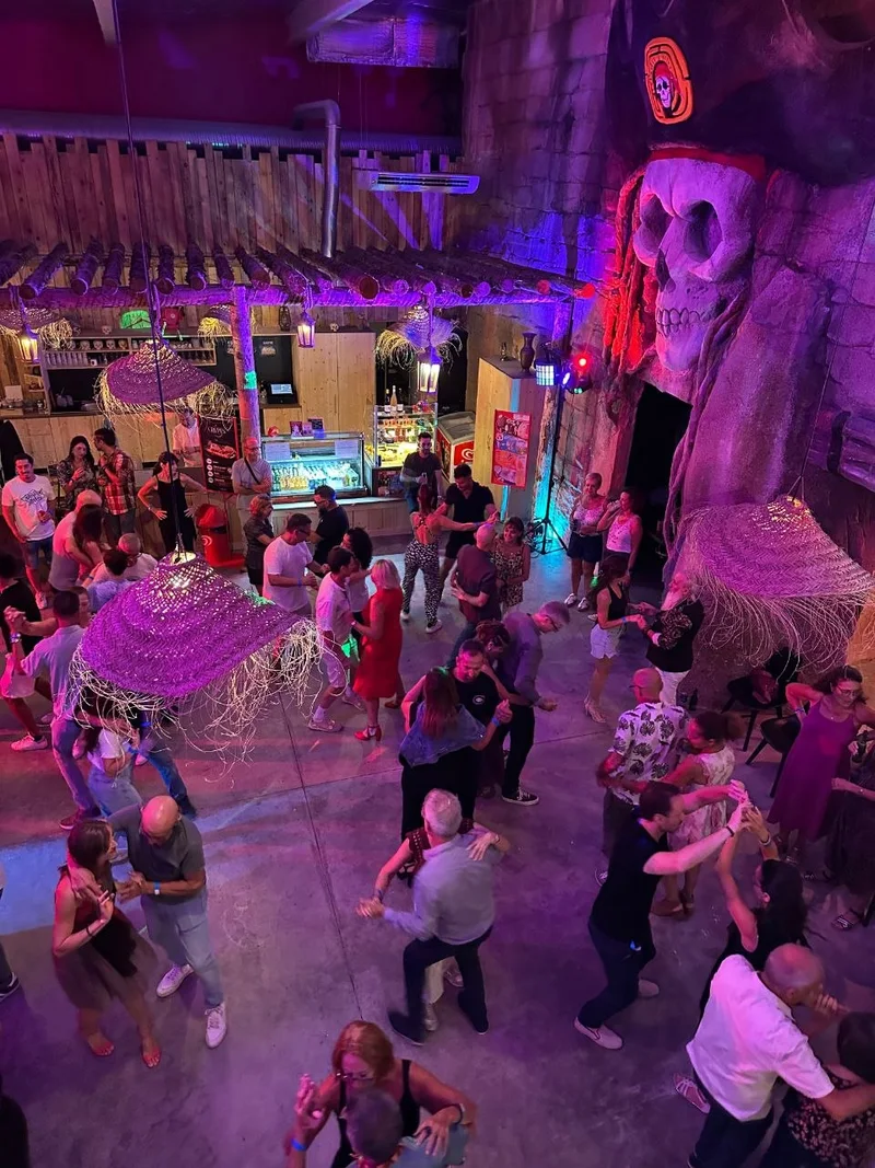 Une soirée dans la grande salle de Défis Pirate Perpignan, vue d'en haut : la piste pleine sous le crâne géant et les lumières violettes, le bar au fond