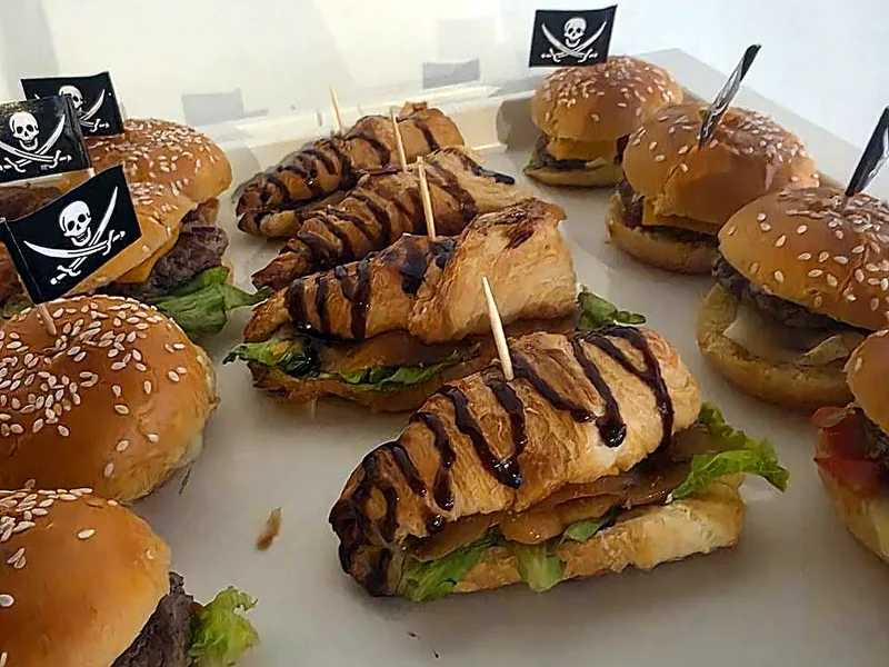 Mini-burgers et croissants garnis, piqués de drapeaux pirates