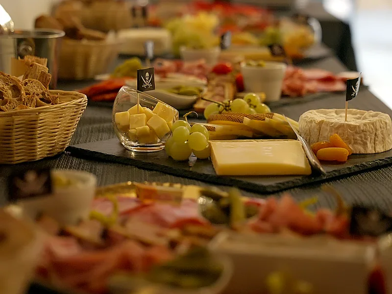 La longue table du buffet d'entreprise : fromages, raisin, charcuterie et corbeilles de pain