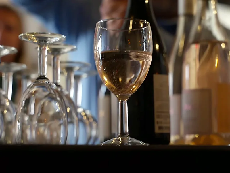 Un verre de vin blanc au bar, devant les bouteilles et les verres