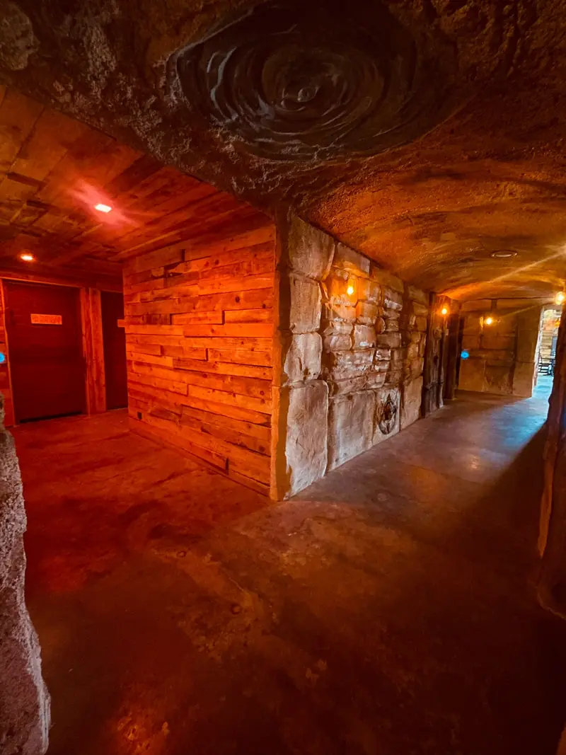 Un couloir de bois et de pierre baigné de lumière rouge
