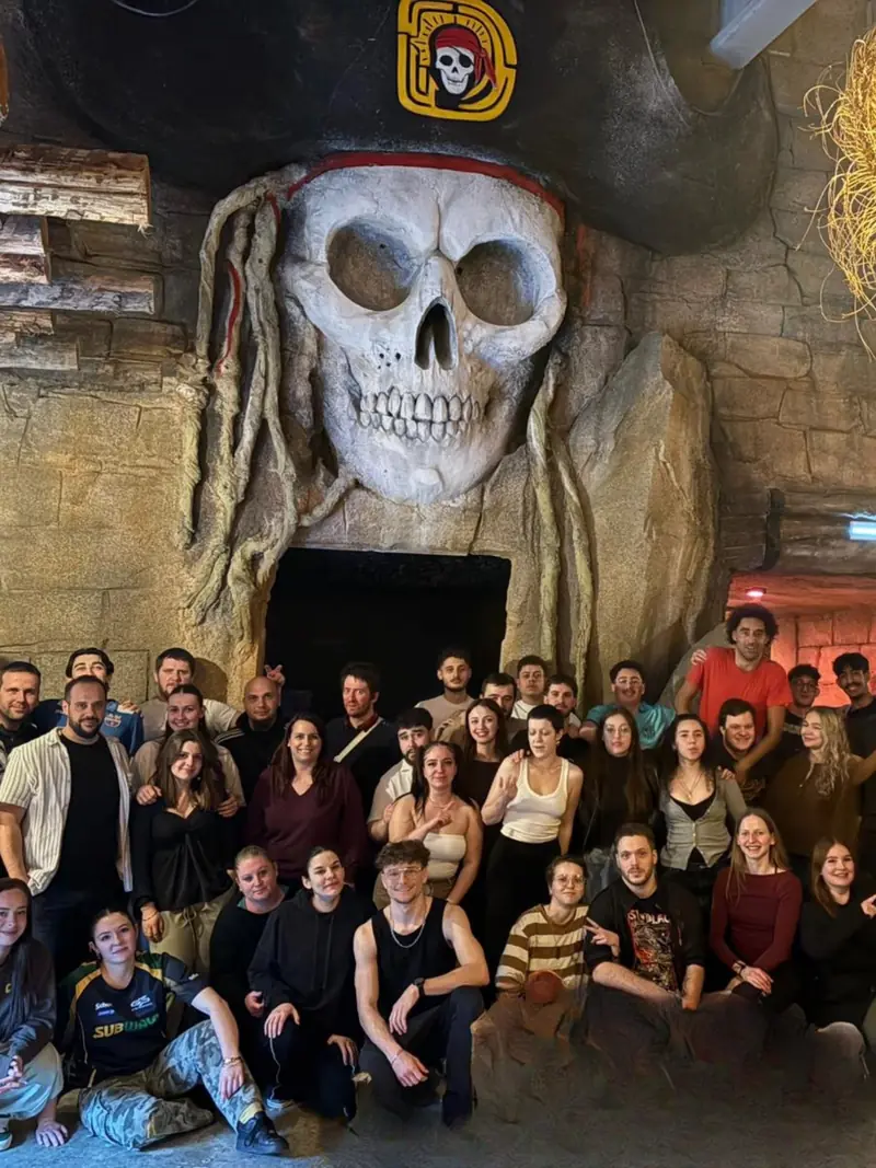 Un grand groupe de collègues réuni sous le crâne géant de Défis Pirate après la mission
