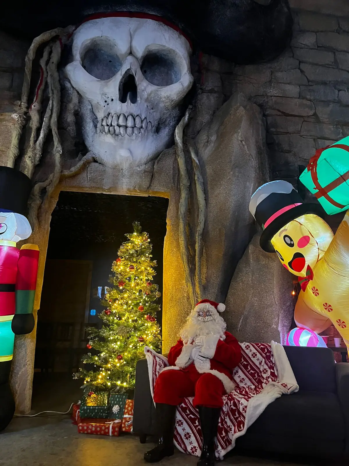 Le Père Noël assis sous le crâne pirate géant, à côté du sapin illuminé de Défis Pirate à Perpignan