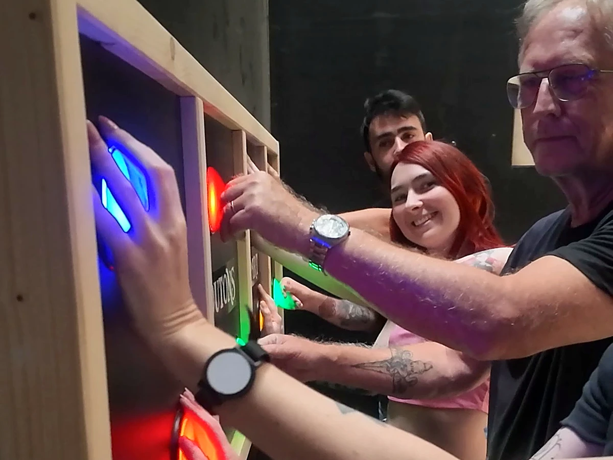 Une équipe appuie ensemble sur les boutons lumineux d'un mur de défi